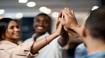 Handschlag zur Begrüßung: Multiethnische Gruppe von Frauen und Männern begrüßt sich mit High Five.